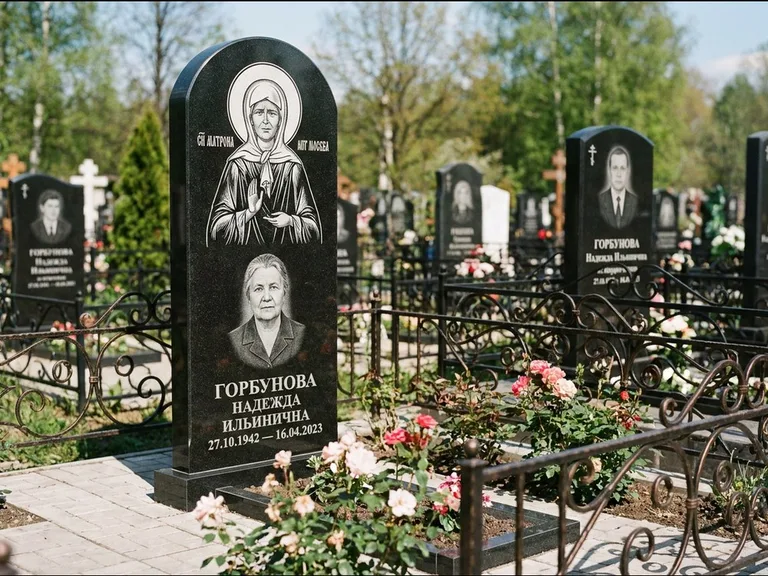 Памятник с гравировкой иконы: стела с арочным верхом и киотом под образ — гравировка образа Матроны Московской, гранитный цоколь с тёмной плиткой, работа «Ковалёв» в Магнитогорске