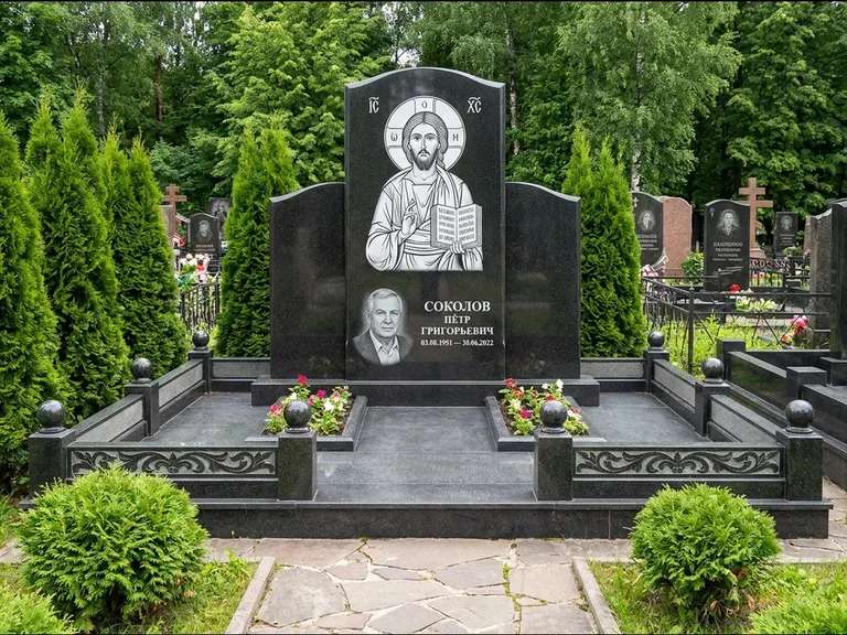 Памятник с гравировкой иконы: широкая горизонтальная лежачая плита-стела — икона в резной рамке-киоте, серая гравийная отсыпка с бордюром, работа «Богданова» в Магнитогорске