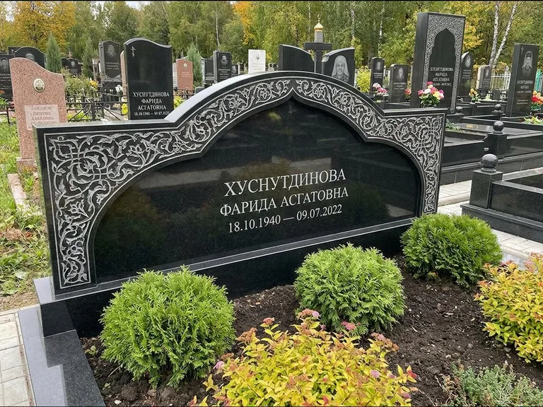 Мусульманский памятник: вытянутая горизонтальная семейная стела с аркой — белая гравировка силуэта мечети с минаретами, участок с декоративными кустами, работа «Зарипова» в Магнитогорске