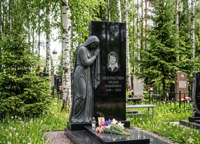 Гранитная фигура скорбящего мужчины у чёрной стелы в Магнитогорске